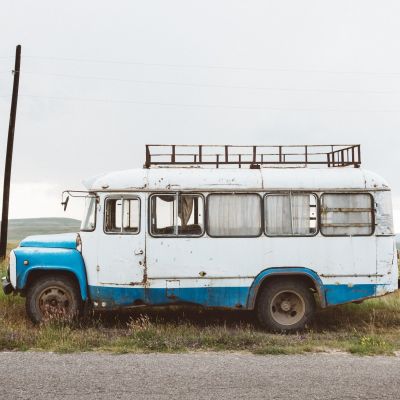 Closeup shot of an old minibus on a green landscape under a cloudy sky